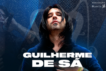 Cartaz do arquivo com fundo azul texturizado. Ao centro, o cantor Guilherme de Sá aparece de olhos fechados e cabeça levemente erguida, com cabelos longos e escuros sobre o rosto. O nome "GUILHERME DE SÁ" está escrito em letras brancas grandes na parte inferior.