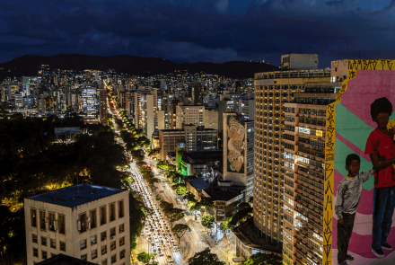 Vista de cima de uma Avenida da cidade de Belo Horizonte a noite, com muitos veículos e edifícios.
