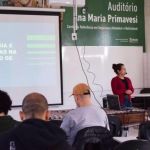 Imagem de uma pessoa apresentando um trabalho a frente de um sala de aula