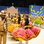 Apresentação de um grupo de quadrilha dançando, com um casal em destaque.